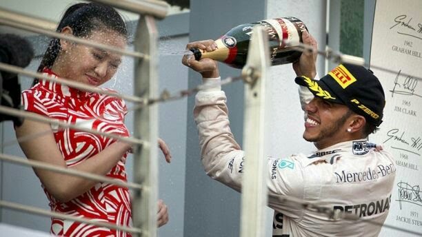 Selebrasi Lewis Hamilton dengan menyemprotkan sampainye ke wajah grid Girls di F1 China 2015. (Foto : ist)