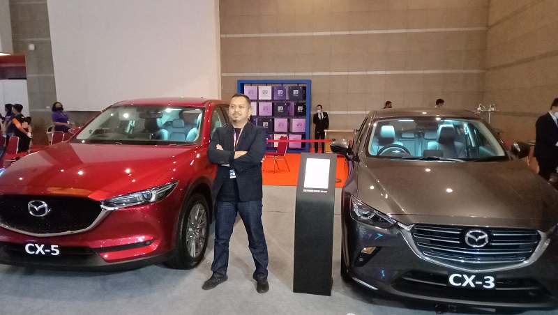 Branch Manager Mazda Raden Saleh, Obie Magribie berpose bersama dua mobil Mazda terlaris di pameran IIMS Hybrid 2021