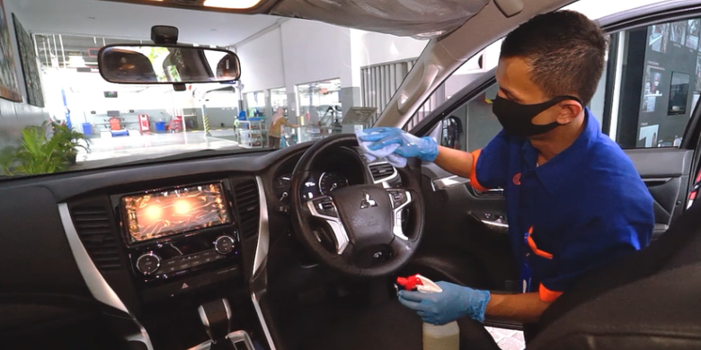 Teknisi Mitsubihi melakukan penyemprotan disinfektan pada mobil konsumen disebuah dealernya