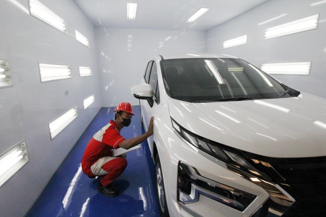Seorang teknisi Mitsubishi mengecek finishing repair bodi mobil konsumen