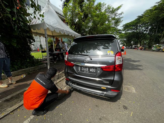 Teknisi melakukan uji emisi pada mobil masyarakat di Tangerang Selatan