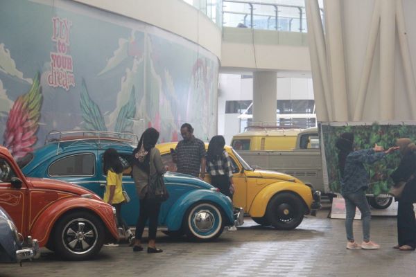 Para pengunjung pameran berfoto bersama mobil legendaris VW Beetle