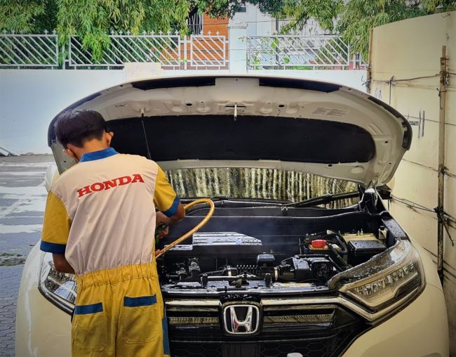 Seorang tenaga mekanik Honda sementara memeriksa mobil mobil bekas