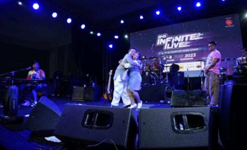 Hedy Yunus dari Kahitna memeluk seorang penggemarnya di atas panggung IIMS Infinite Live pameran otomotif IIMS 2023 Surabaya, Minggu (4/6/2023)