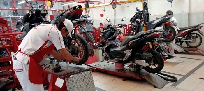 Mekanik bengkel Honda Motor sementara menservis tunggangan konsumen