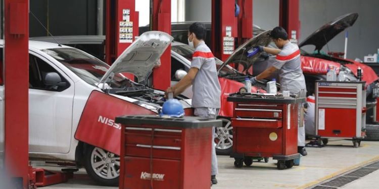 Mekanik Nissan sementara melakukan perawatan mobil konsumen