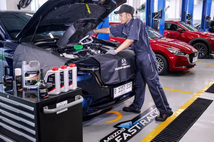 Seorang mekanik Mazda melakukan pemeriksaan dan perawatan mobil konsumen